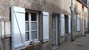 A row of windows with shutters, a stone wall, and a number '7' sign.