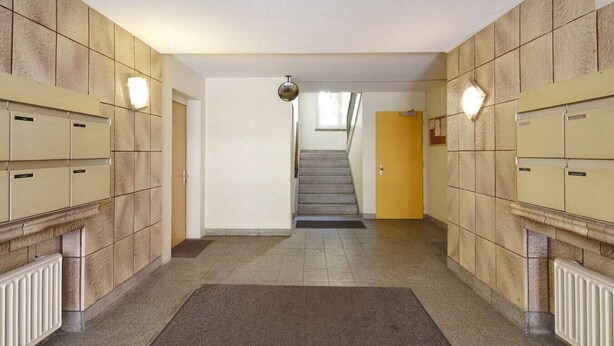 A hallway with lockers on both sides, a carpeted floor, and a staircase leading to another floor. - Cozy studio near train station (Wille 7) (Zürich)