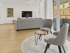 A modern living room with a grey sofa, two armchairs, a coffee table, and a TV. - 2BR flat in the city center (West 12) (Zürich)