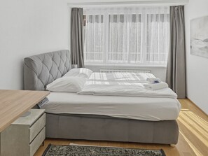 A bedroom with a bed, a bedside table, a radiator, and a window with curtains. - 2BR flat in the city center (West 12) (Zürich)
