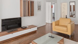 A modern living room with a flat-screen TV, wooden cabinet, sofa, and glass coffee table. - 2BR near lake (Flower 23) (Zürich)