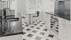 A modern kitchen with a black and white checkered floor, stainless steel appliances, and a window with sheer curtains. - 2BR near lake (Flower 23) (Zürich)