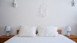 A neatly made bed with white bedding, two bedside lamps with pineapple-shaped bases, and a dreamcatcher hanging on the wall. - BeGuest Feliz Choro (Albufeira)
