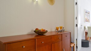 A wooden cabinet with drawers, a bowl of fruit, and two candle holders on top. - BeGuest Feliz Choro (Albufeira)