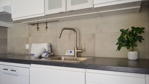 A modern kitchen with white cabinets, a stainless steel sink, and a built-in dishwasher. - BeGuest Feliz Choro (Albufeira)