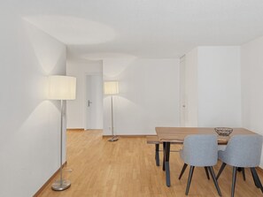 A modern dining area with a wooden table, two grey chairs, and two floor lamps. - Modern 2BR in the city center - Hösch 12 (Zürich)