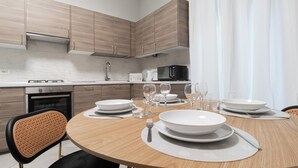 A modern kitchen with wooden cabinets, a microwave, and a dining table set with plates, glasses, and cutlery.
