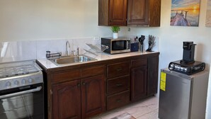 Une cuisine avec des meubles en bois, un évier en acier inoxydable, un four à micro-ondes, une machine à café et une cuisinière.
