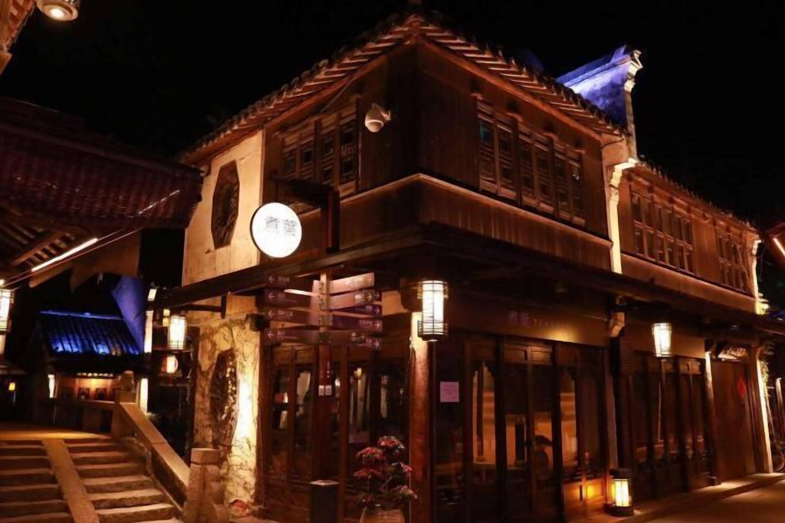 A traditional building with a staircase leading to the entrance, a signboard, and a lantern.