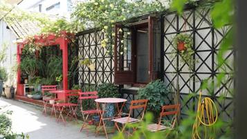 An outdoor seating area with tables and chairs, surrounded by plants and a lattice wall.