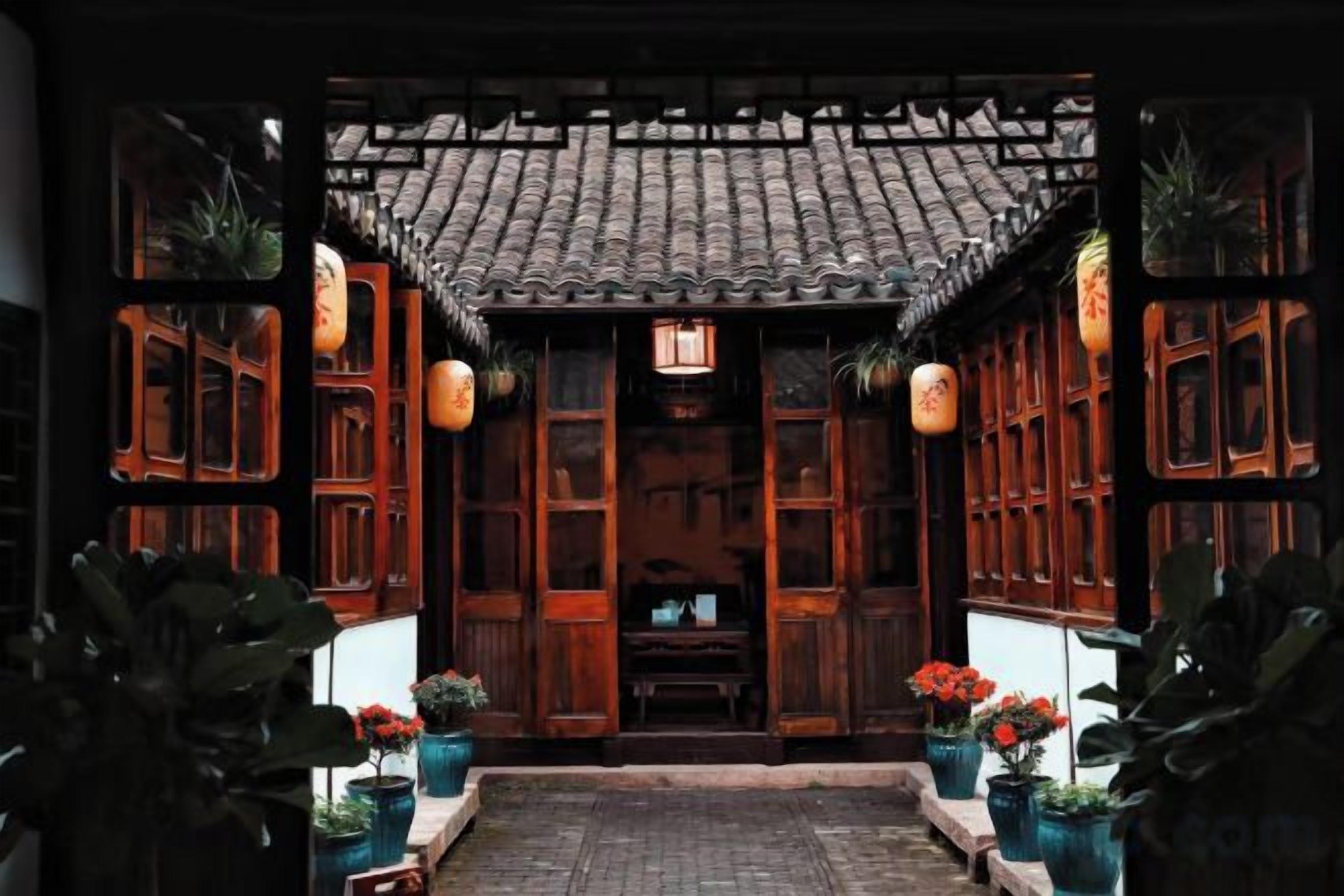 A traditional wooden structure with a tiled roof, potted plants, and hanging lanterns.