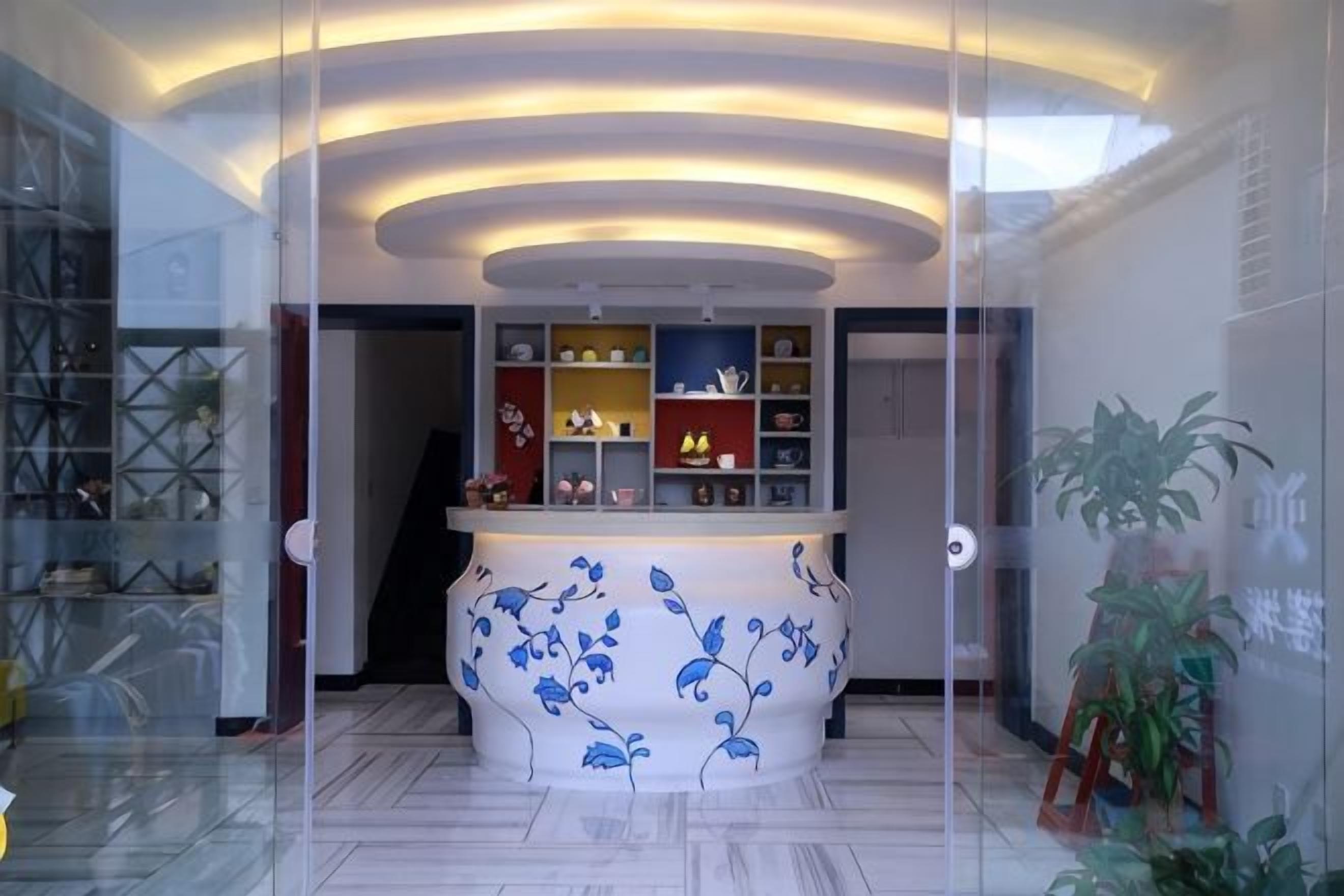A reception area with a curved counter, glass partitions, and shelves with decorative items.