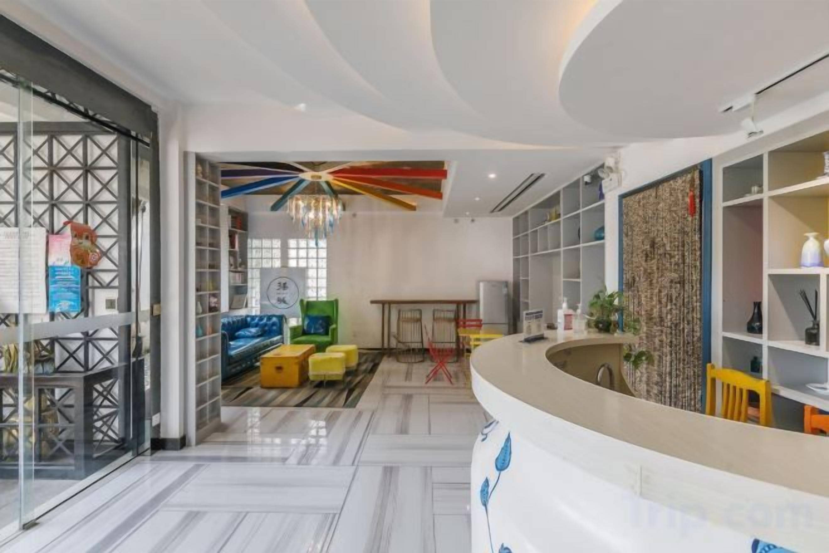 Un hall d'hôtel moderne comprenant un comptoir d'accueil, un espace salon et un plafond décoratif.