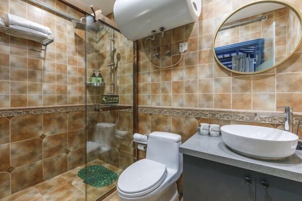 A bathroom with a glass-enclosed shower, a toilet, a sink, and a mirror.