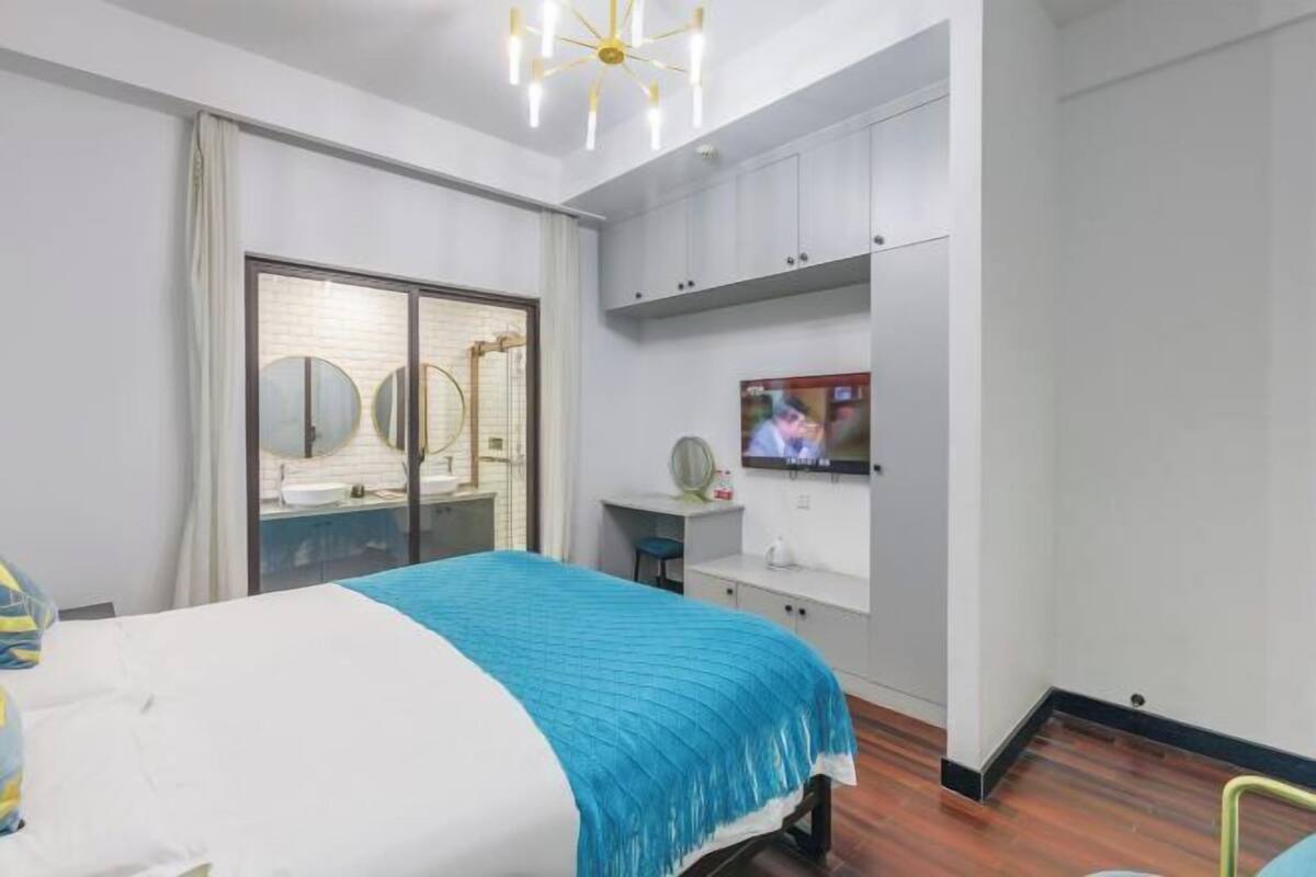 A hotel room with a bed, a TV, a desk, and a wardrobe.