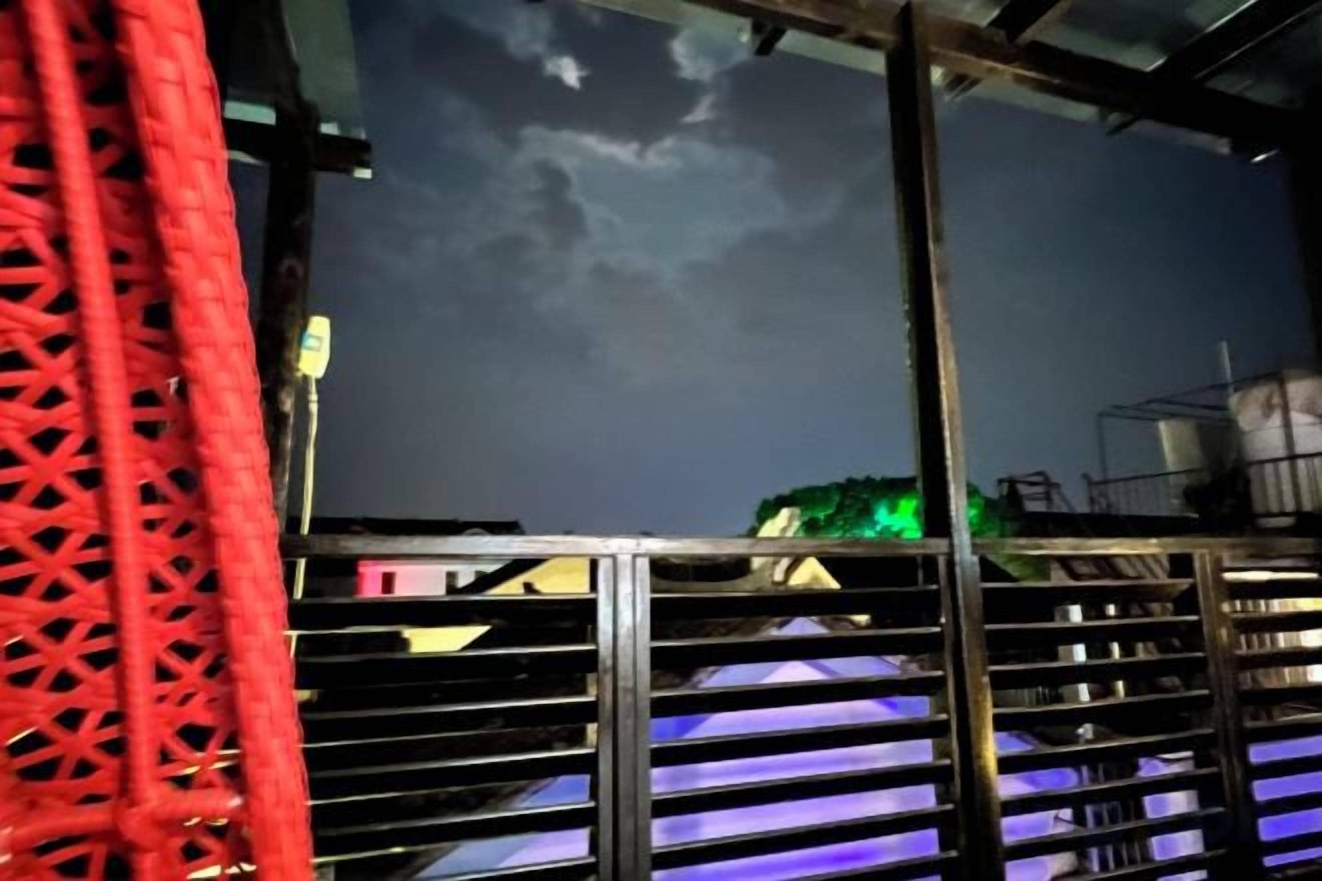 A room with a metal railing, a patterned curtain, and a view of the sky.