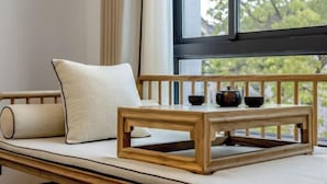 A wooden bench with cushions and a table with teapots. - Your City Pinghua Impression Inn (Kunshan)