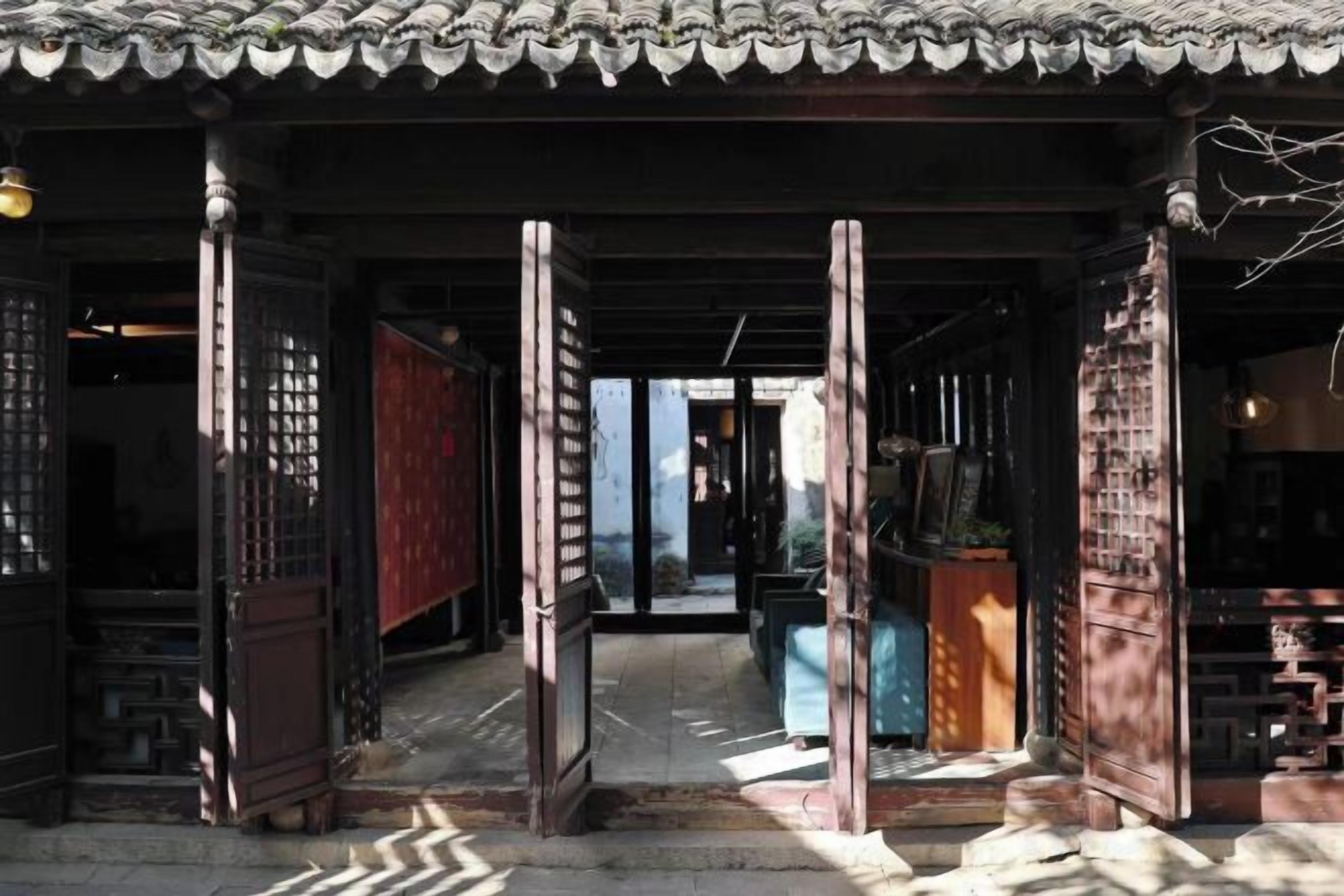 Une entrée de style japonais traditionnel, avec un toit en tuiles, des piliers en bois et des portes coulissantes.