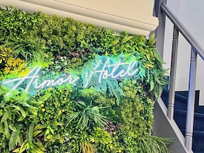 A lush vertical garden with a neon sign reading "Armor Hotel."