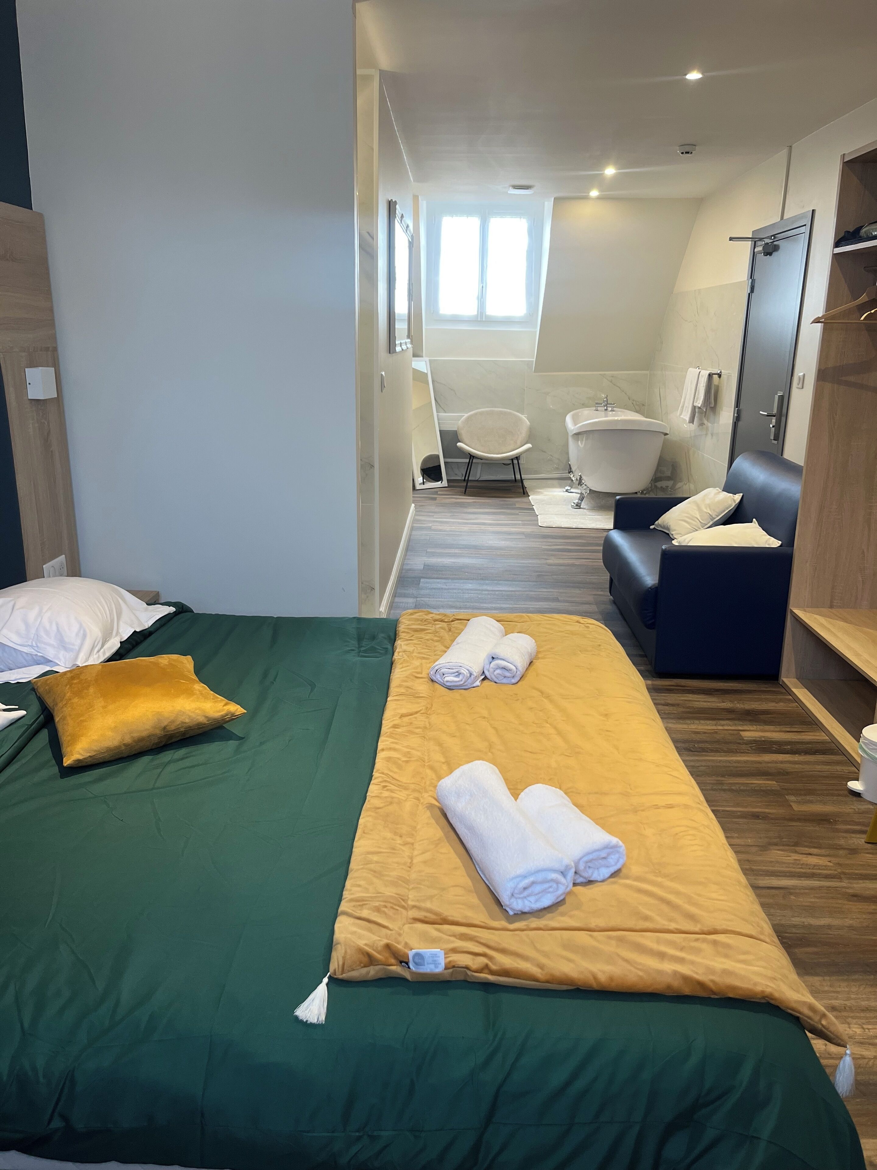 Una habitación de hotel con cama, sofá, bañera y zona de ducha.