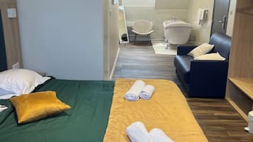 Una habitación de hotel con cama, sofá, bañera y zona de ducha.