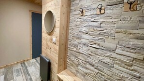 A room with a wooden ceiling, a stone wall with hooks, and a round mirror. - Beautiful studio with magnificent view (Briançon)