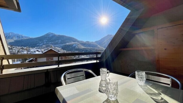 A table with two glasses and a mug on a balcony overlooking a mountainous landscape. - Beautiful studio with magnificent view (Briançon)