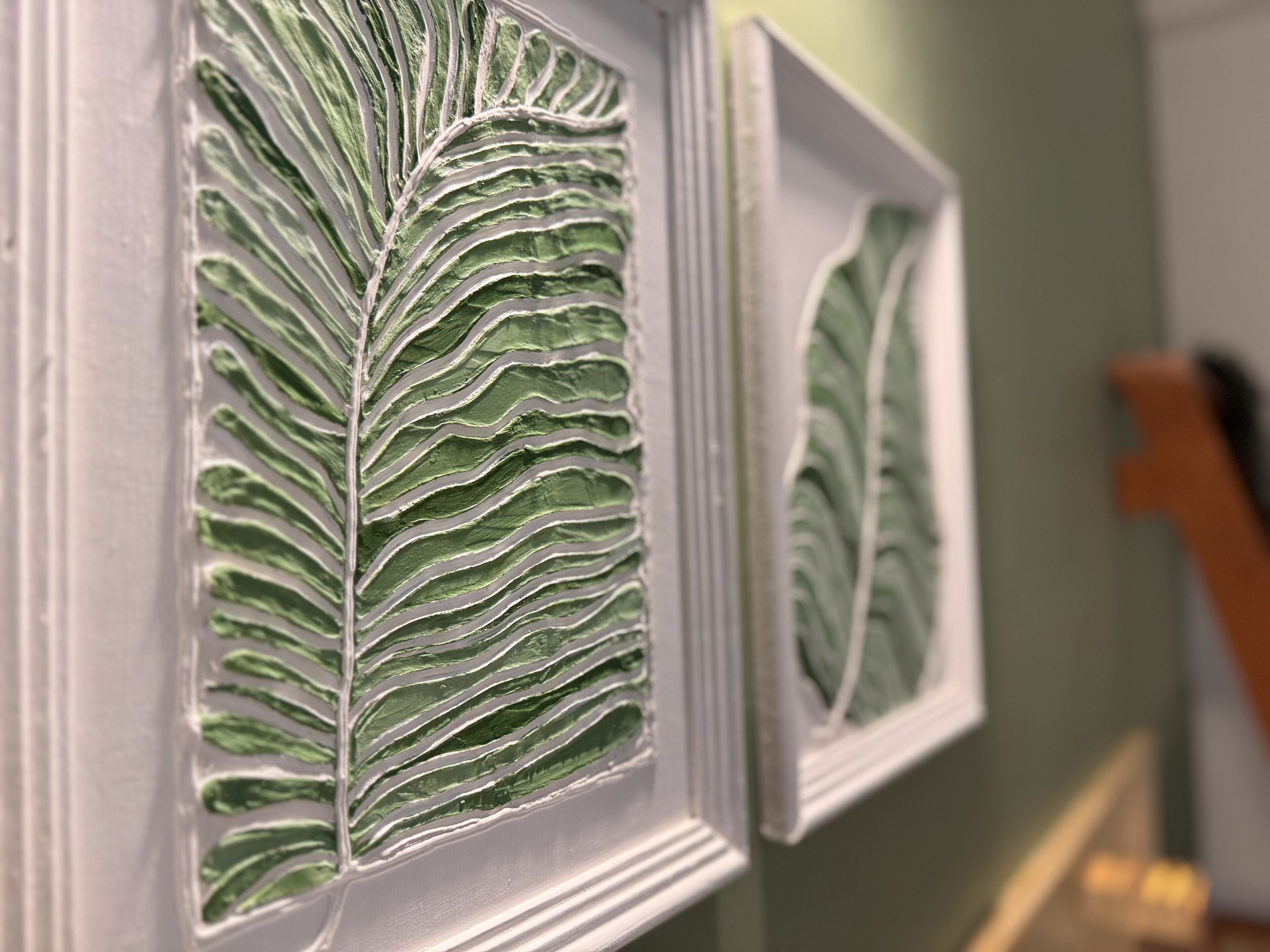 Un gros plan d’une œuvre d’art représentant une feuille encadrée, dont le motif présente une texture particulière.