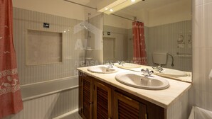 Une salle de bain avec deux lavabos, un miroir et une douche.