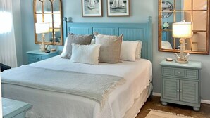 Un dormitorio con una cama, dos mesitas de noche, un espejo y decoración en la pared.