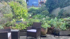 Een terras buiten met rieten meubilair en plantenpotten.