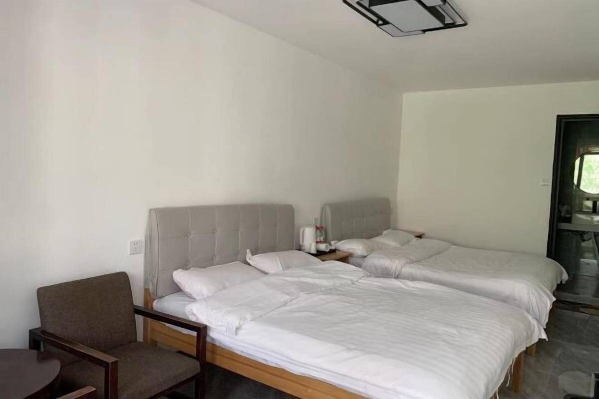 A hotel room with two beds, a chair, and a small table.