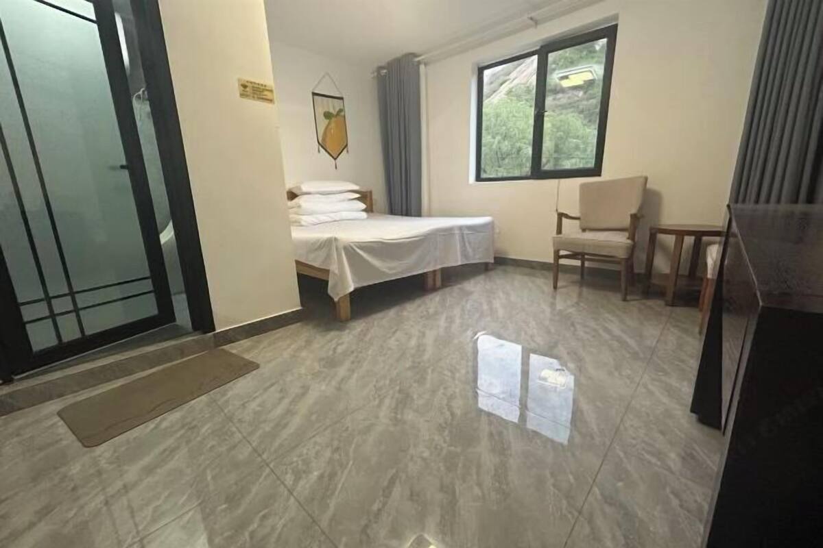 A room with a bed, a chair, a window, and a door.