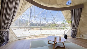 A room with a large window, a table with a mug, and a potted plant. - NAGOMI CAMP (Nasushiobara)