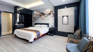 A modern hotel room with a large bed, bedside table, and a seating area with a glass table and chairs. - Lotto Hotel (Dongxing)