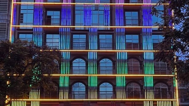 A hotel facade with illuminated vertical lines and a sign indicating it is a hotel. - Lotto Hotel (Dongxing)