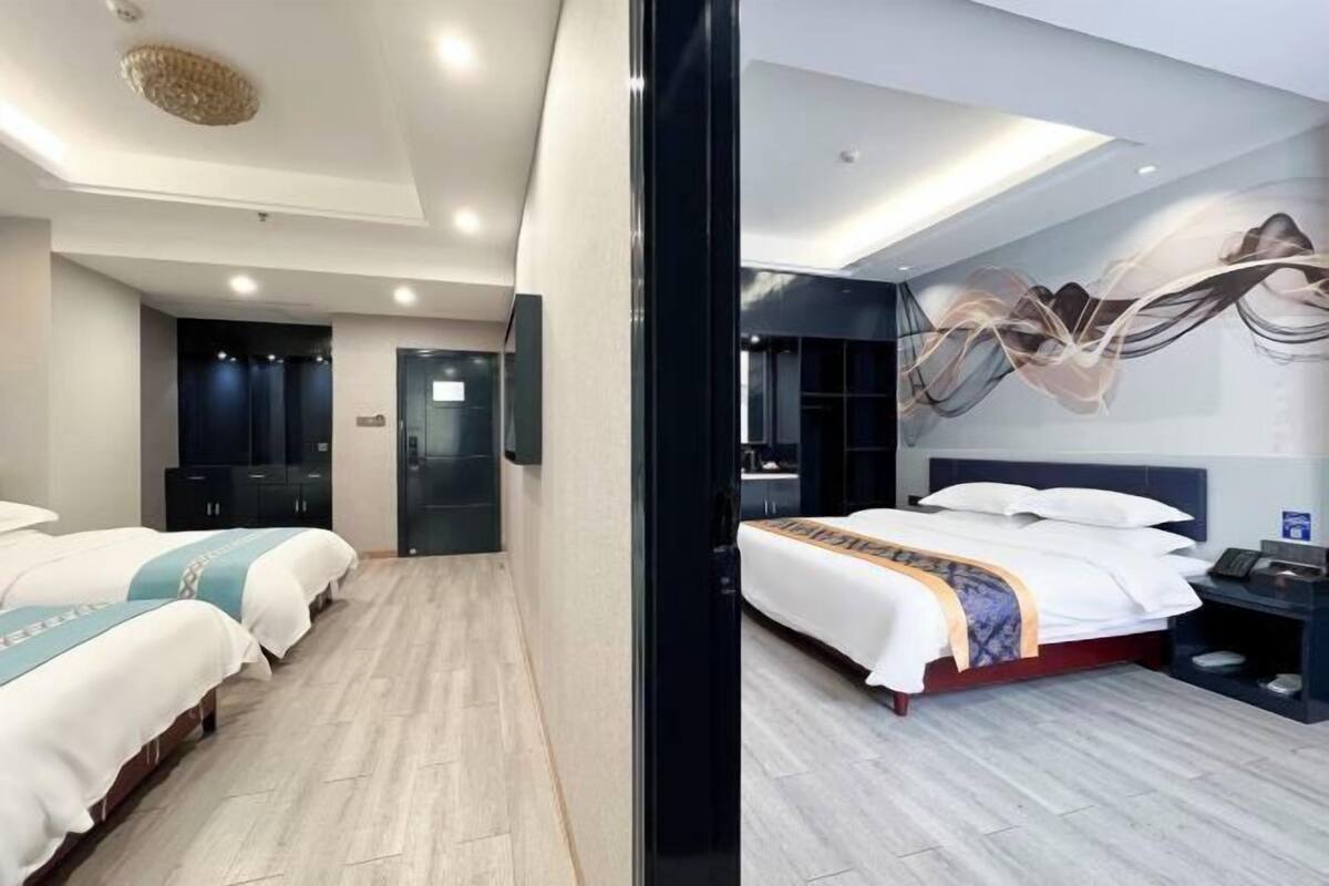 Una habitación de hotel con dos camas, un escritorio, una silla y un armario.
