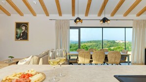 Un coin repas avec une table dressée pour deux personnes, un tableau accroché au mur et une vue panoramique à travers de grandes fenêtres.