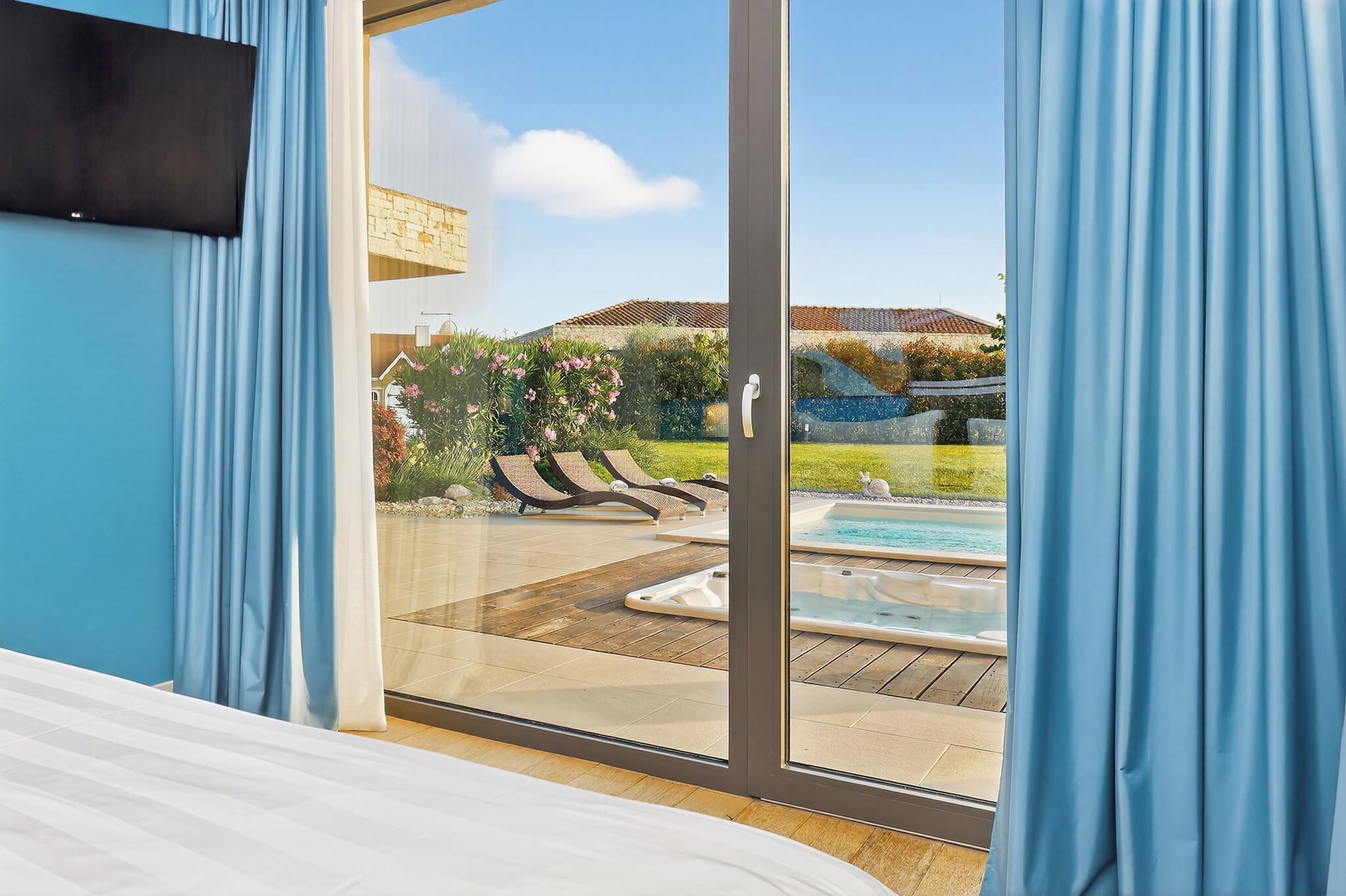 Ein Schlafzimmer mit einer Schiebetür zu einem Außenbereich mit Pool und Liegestühlen.