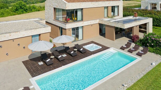 Une maison moderne à deux étages, dotée d’une piscine, d’un espace salon extérieur et offrant une vue sur la campagne.