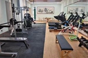A gym with exercise equipment, a bench, and a table with chairs.