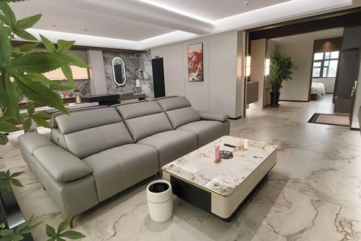A modern living room with a grey sofa, a marble coffee table, and a small trash bin.