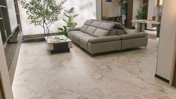 A modern living room with a sectional sofa, a coffee table, and a marble floor.