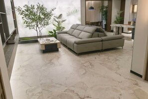 A modern living room with a sectional sofa, a coffee table, and a marble floor.