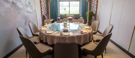 A round table with chairs, a glass centerpiece, and a view of the outdoors through a window.
