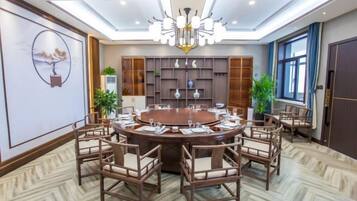 A conference room with a round table, chairs, a chandelier, and a large window.