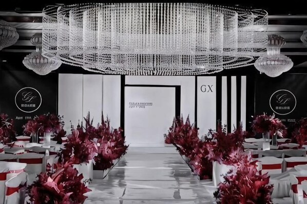 A formal event space with a chandelier, rows of chairs, and floral decorations.