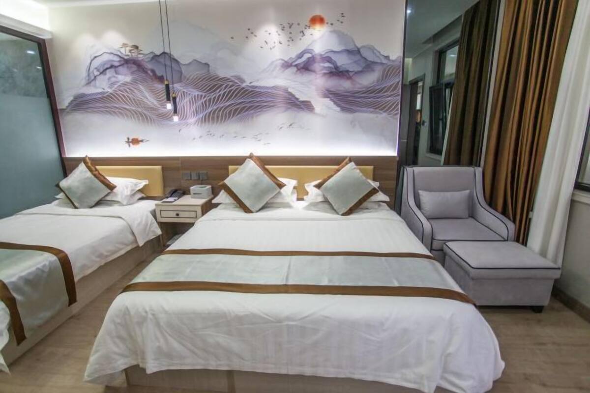 A hotel room with two beds, a large wall mural, a modern chair, and a nightstand.