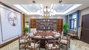 A conference room with a round table, chairs, and a chandelier.