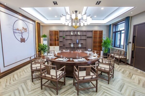 Une salle de conférence équipée d’une table ronde, de chaises et d’un lustre.